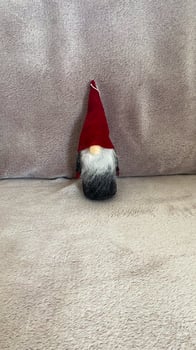 A small gnome with a red hat sitting on a couch photo