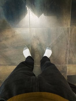 A person standing on a tiled floor with their feet in socks photo