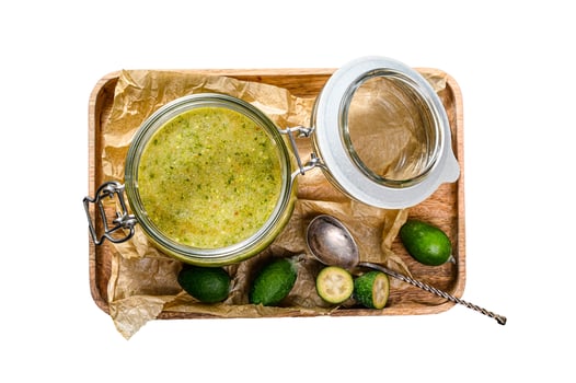 Green feijoa jam on a wooden chopping Board in a glass jar. Natural homemade dessert. Isolated on white background. Top view. photo