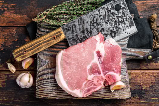 Butcher cutting board with Raw T-bone pork chop meat steak. Wooden background. Top view photo