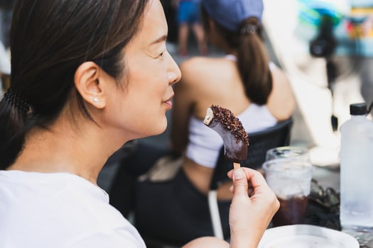 Middle aged woman enjoy eating frozen banana with chocolate on a Stick. photo