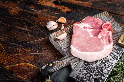 Butcher cutting board with Raw T-bone pork chop meat steak. Wooden background. Top view. Copy space photo