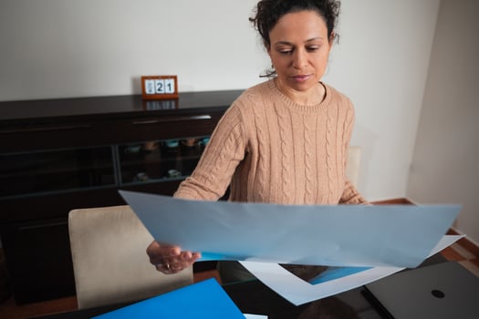 Woman reviewing documents at home office with focused expression photo