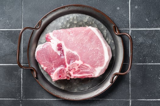 Raw pork t bone chop meat steak. Black background. Top view photo