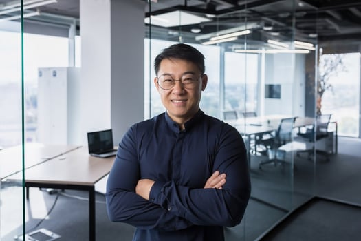 Portrait of successful and experienced mature asian businessman, man working inside modern office, smiling and looking at camera with crossed arms, director investor in glasses and shirt. photo