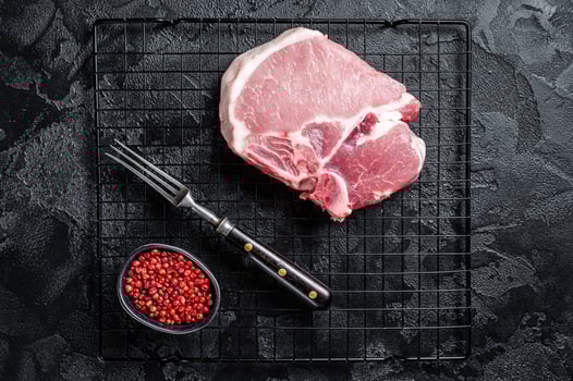 Uncooked Raw pork T bone chop meat steak on grill. Black background. Top view photo