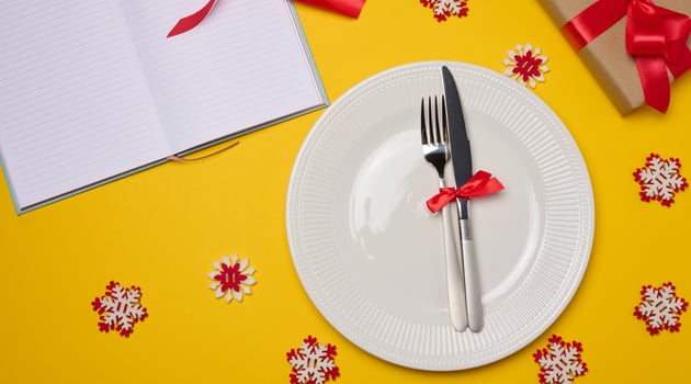 Empty white round plate, fork and knife on yellow background, top view photo