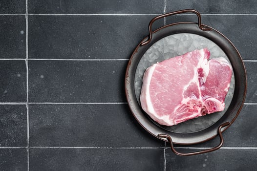 Raw pork t bone chop meat steak. Black background. Top view. Copy space photo