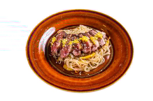 Noodles with duck breast fillet steak on a plate. Isolated on white background. photo