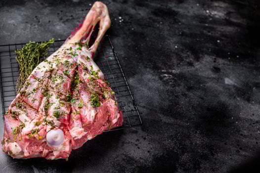 Whole raw Goat leg Marinated with herbs and olive oil. black background. top view photo