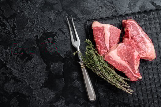Topside sirloin beef cut, raw meat with spices. Black background. Top view. Copy space photo