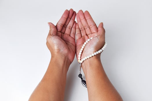 People's hands are praying using prayer beads with an white background photo