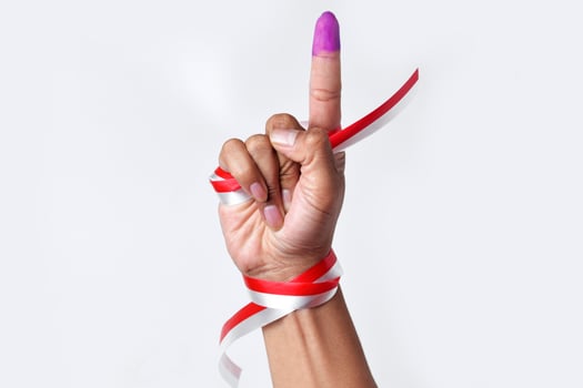 A human hand points one finger in blue ink as a form of election photo