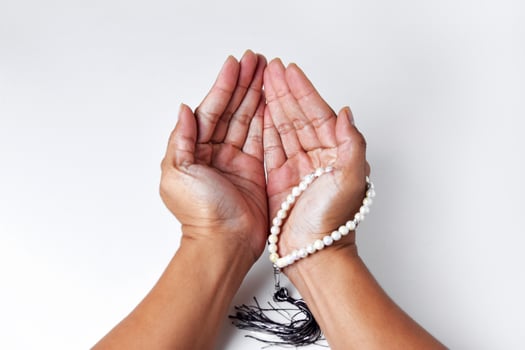 People's hands are praying using prayer beads with an white background photo