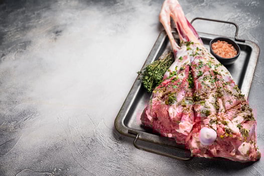 Marinated with herbs and olive oil raw lamb leg. white background. top view photo