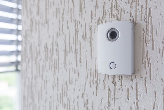 A white incoming electronic doorbell with a camera on the wall of the building, office. photo