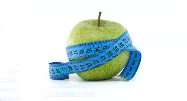 Green Apple Wrapped with Blue Measuring Tape for Health Concept photo