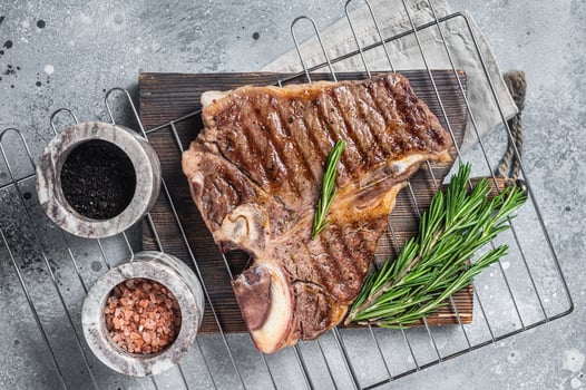 Grilled t-bone porterhouse beef meat Steak on a grill with spices. Gray background. Top view photo