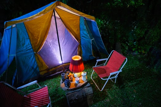 Camping tents in the morning, vintage cabin tents, antique oil lamps, retro chairs, and a group of camping tents with outdoor coffee-making facilities on wooden tables in a forest photo