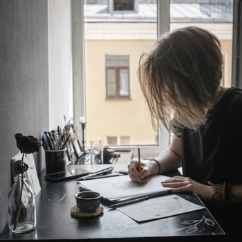 A creative workspace featuring an artist at their desk engaged in the act of drawing thoughtfully photo