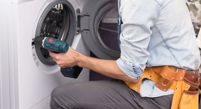 Young handyman fixing washing machine, closeup. Laundry day. photo