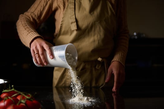 Home cook sifting flour onto a kitchen surface for baking preparation photo