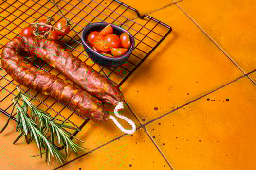 Spanish Chorizo sausage, dry cured pork with herbs and spices. Orange background. Top view. Copy space photo