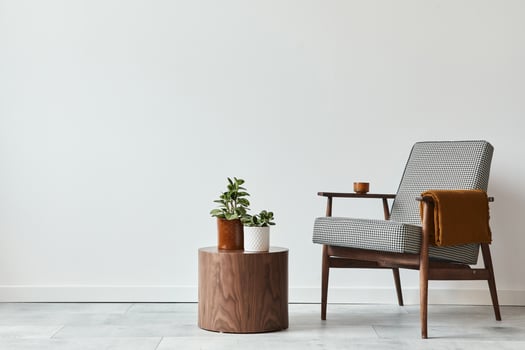 Minimalist composition of living room with design armchair, wooden stool, decoration, plants, copy space and personal accessories in modern home decor. White wall. Template. photo