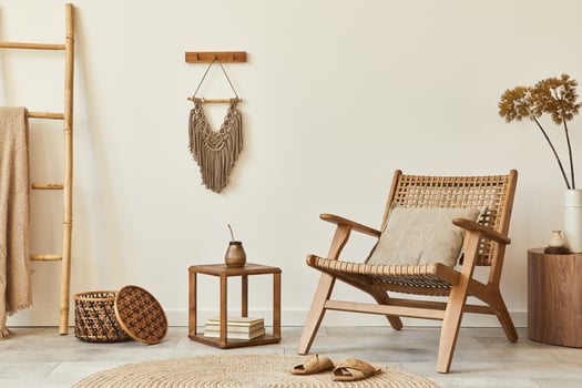 Stylish interior design of living room with wooden armchair, coffee table, furniture, rattan decoration, dried flowers and elegant personal accessories. Copy space white wall. Template. photo