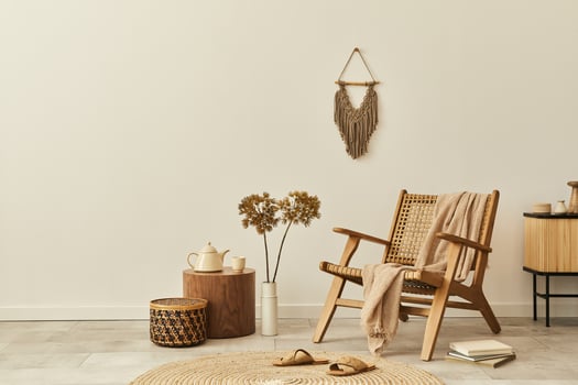 Stylish interior design of living room with wooden armchair, coffee table, furniture, rattan decoration, dried flowers and elegant personal accessories. Copy space white wall. Template. photo