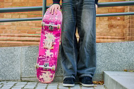 Skateboarder holding worn pink skateboard at street photo