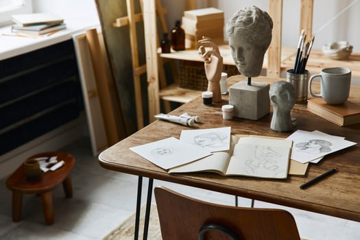 Unique artist workspace interior with stylish desk, wooden easel, bookcase, artworks, painting accessories, decoration and elegant personal stuff. Modern work room for artist. Template. photo