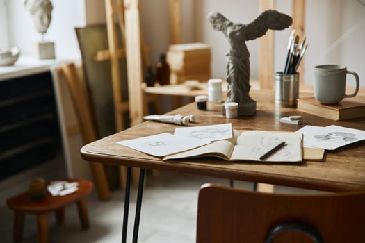 Unique artist workspace interior with stylish desk, wooden easel, bookcase, artworks, painting accessories, decoration and elegant personal stuff. Modern work room for artist. Template. photo
