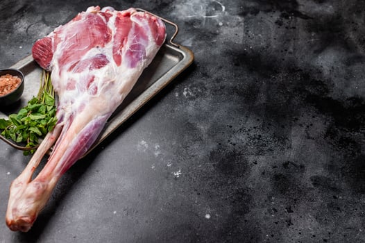 Uncooked whole mutton leg, raw organic lamb meat. black background. top view photo
