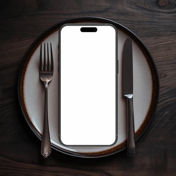 Black smartphone mockup template with blank screen on plate with knife and fork photo