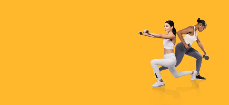 Two women perform strength training exercises using dumbbells in a bright indoor space. They focus on their routines with determination and concentration, showcasing a healthy lifestyle. photo