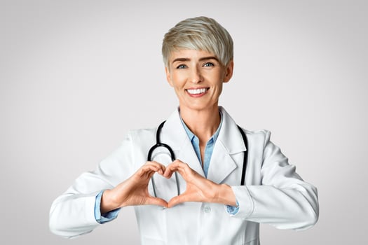 Happy woman doctor shows heart with hands isolated on gray background photo