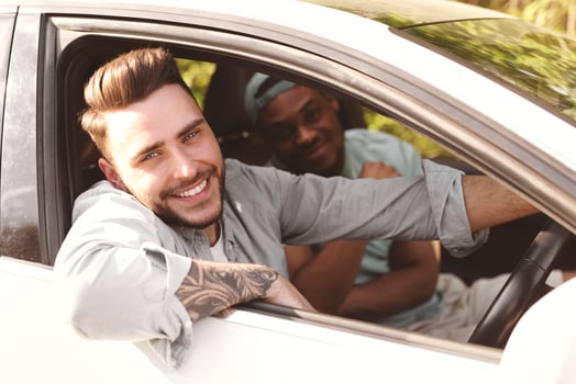 Happy young international friends riding their car, looking through windows, going on road trip together. Millennial multiracial students having summertime vacation, enjoying travel photo