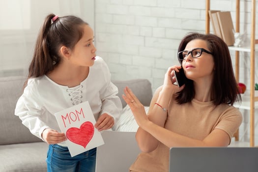 Teen girl giving festive card to her working mother, parent being too busy to pay attention. Business woman having no time for her child, doing online job during coronavirus lockdown photo