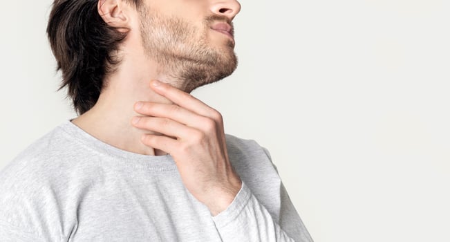 Man with throat sore is holding aching spot, cropped, panorama photo