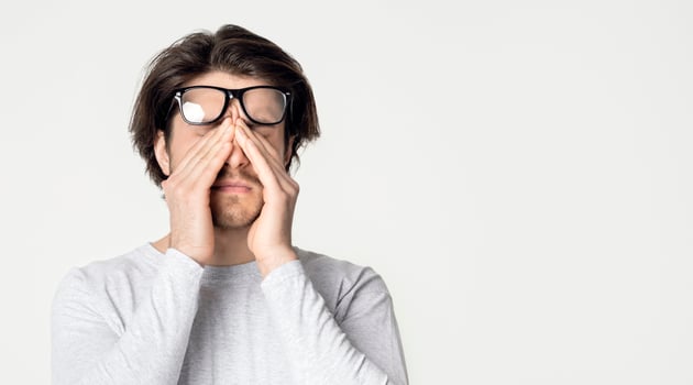 Strong migraine and eyes pain. Guy raises glasses and rubs his eyes photo