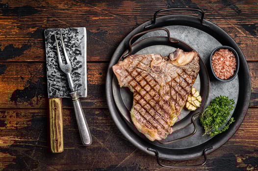 BBQ Grilled T-bone or Porterhouse beef meat Steak on a steel tray with herbs. Wooden background. Top view photo
