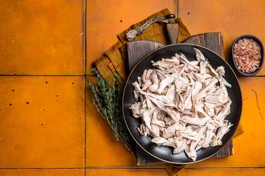Shredded chicken meat in a plate. Orange background. Top view. Copy space photo