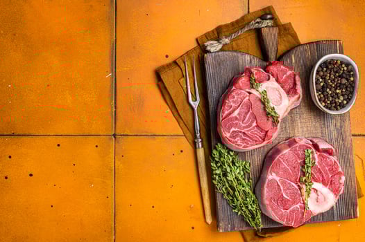 Osso buco Veal shank, raw cross cut veal shank, Italian Ossobuco. Orange background. Top view. Copy space photo