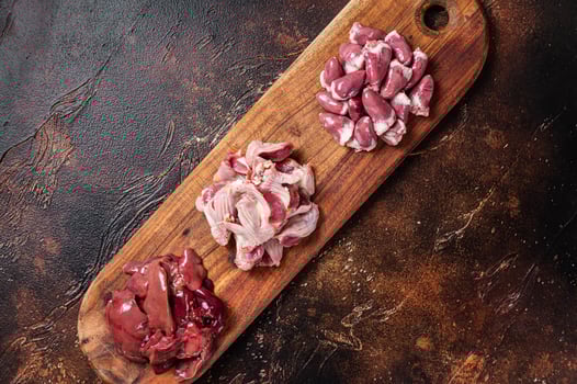 Raw chicken offals, liver, hearts, gizzards Stomach meat set. Dark background. Top view photo