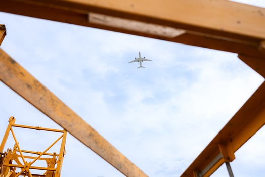 Tower crane in at construction site with air plane on sky in the background photo
