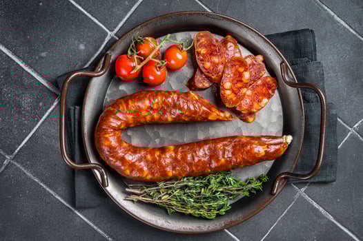 Sliced Chorizo sausage, slices of dry cured pork with herbs and spices. Black background. Top view photo