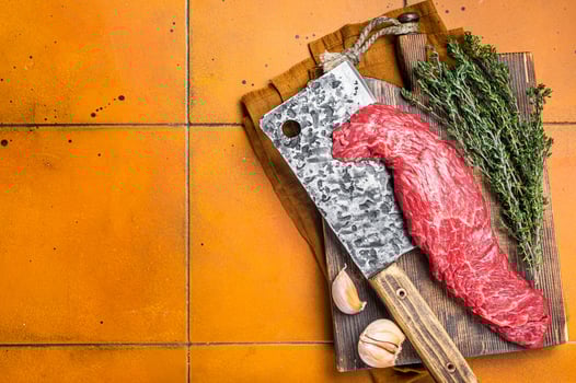 Fresh Raw Machete beef meat steak or hanging tender cut on butcher cutting board. Orange background. Top view. Copy space photo