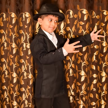 Cute Indian Boy posing with dance step, Asian child model shoot with black coat, pant and white shirt, Kid lifestyle concept shoot indoor photo