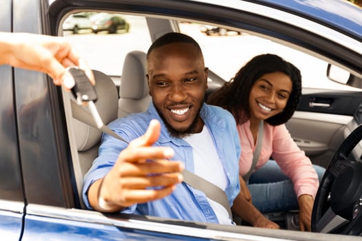 Car Sales. Manager giving new auto key to happy young black couple at dealership store, selective focus. Excited African American customers buying vehicle from salesman seller at automobile showroom photo